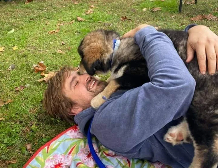 Kenny Fischer playing with a puppy in the grass